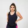 A woman in a black tank top and pink leggings stands confidently,